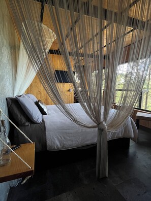 A bed with a canopy, a bedside table with a lamp, and a view of the outdoors. - Mi Refugio Nordico Pequena Cabana (Donato Guerra)