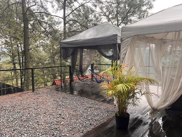 A covered outdoor area with a wooden deck, a black metal railing, and a potted plant. - Mi Refugio Nordico Pequena Cabana (Donato Guerra)