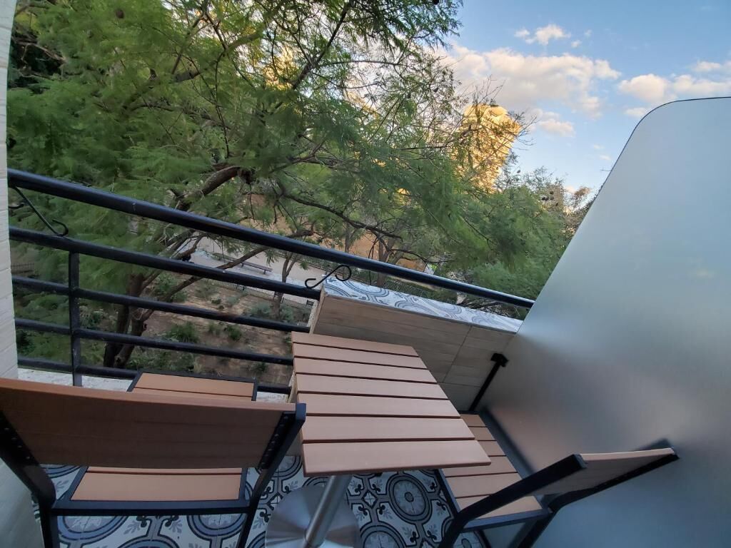 A balcony with a view of trees and a clear sky.