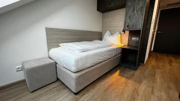 A modern bedroom with a bed, bedside table, and a small stool.
