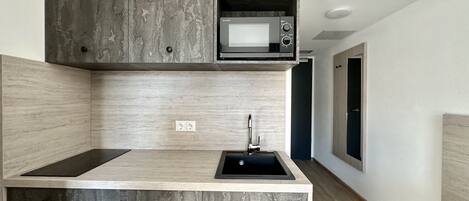Una cocina moderna con microondas integrado, un lavabo y armarios de madera.