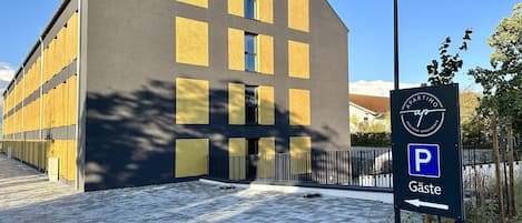 Un edificio moderno con un cartel de estacionamiento que indica la dirección a 'Gäste' (huéspedes).