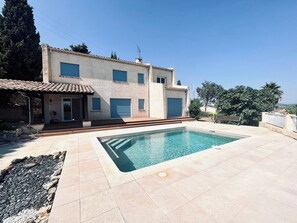 Relax by the outdoor pool surrounded by a serene, tree-lined patio area.