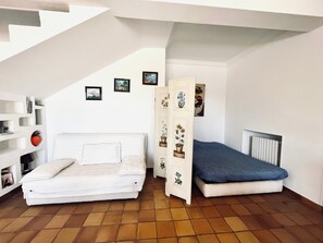 Cozy retreat with a white sofa, platform bed, and decorative cabinet, set against a clean white backdrop.