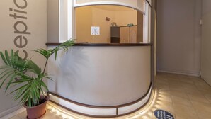 A reception area with a curved reception desk, a potted plant, and a sign on the wall. - Stylish Residence Le Fontane Num2506 (Villasimius)