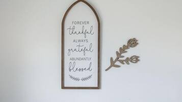 Una cita inspiradora enmarcada en una pared, una lámpara y un sillón con cojín.