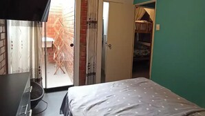Une chambre avec un lit, une télévision, une porte-fenêtre coulissante donnant sur un balcon et un placard.