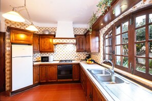 A kitchen with wooden cabinets, a refrigerator, a microwave, a stove, and a sink.