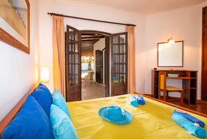 A room with a bed, a table with towels, a mirror, and an open door leading to a balcony. - Villa with heatable pool and BBQ in Albufeira (Albufeira)