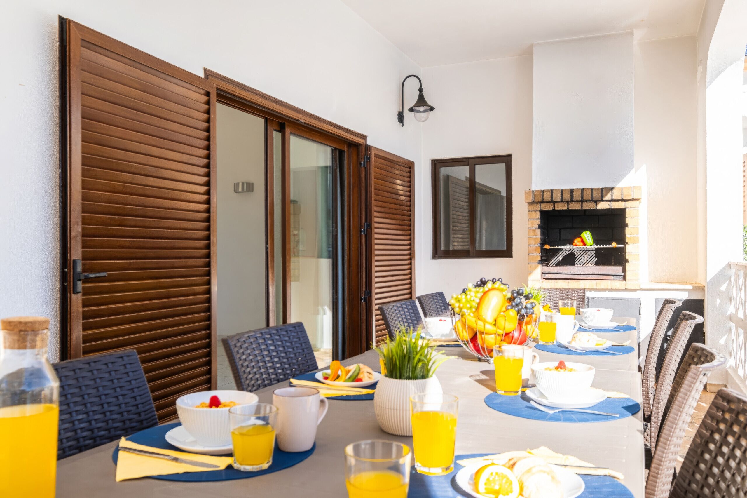 Un coin repas avec une table mise pour le petit-déjeuner, comprenant des assiettes, des bols et des verres de jus d’orange.