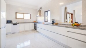 A modern kitchen with white cabinetry, a built-in oven, a microwave, and a coffee maker on the countertop. - Comfort and fun with heatable pool and BBQ (Albufeira)