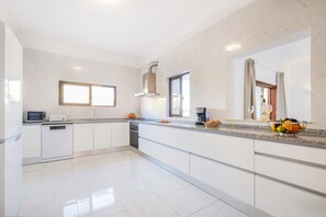 A modern kitchen with white cabinetry, a built-in oven, a microwave, and a coffee maker on the countertop.