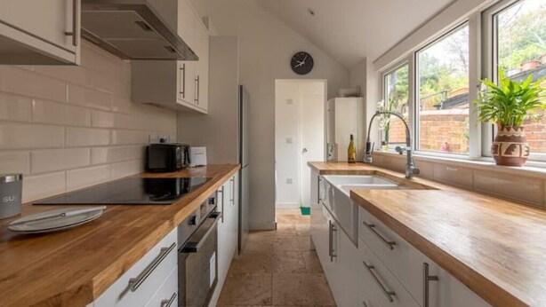 A modern kitchen with wooden countertops, stainless steel appliances, and a view of the backyard through large windows. - 4 Bed Town House - Reading Cent. (Reading)