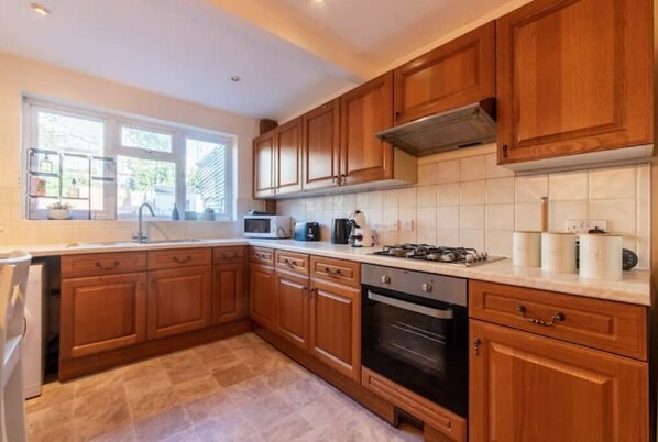 Kitchen features an oven, microwave, and gas stove, with a sink and window.