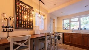 Une cuisine avec un coin bar, une grande affiche représentant des cocktails et un lave-linge.