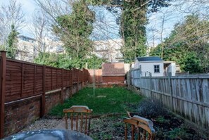 Surrounded by lush trees and a brick wall, this yard features a cozy bench and a charming shed.