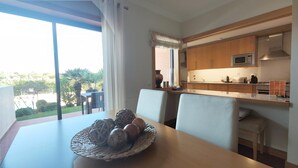 Une cuisine moderne dotée d’une grande fenêtre, un coin repas avec une table et des chaises, et une vue sur l’extérieur.