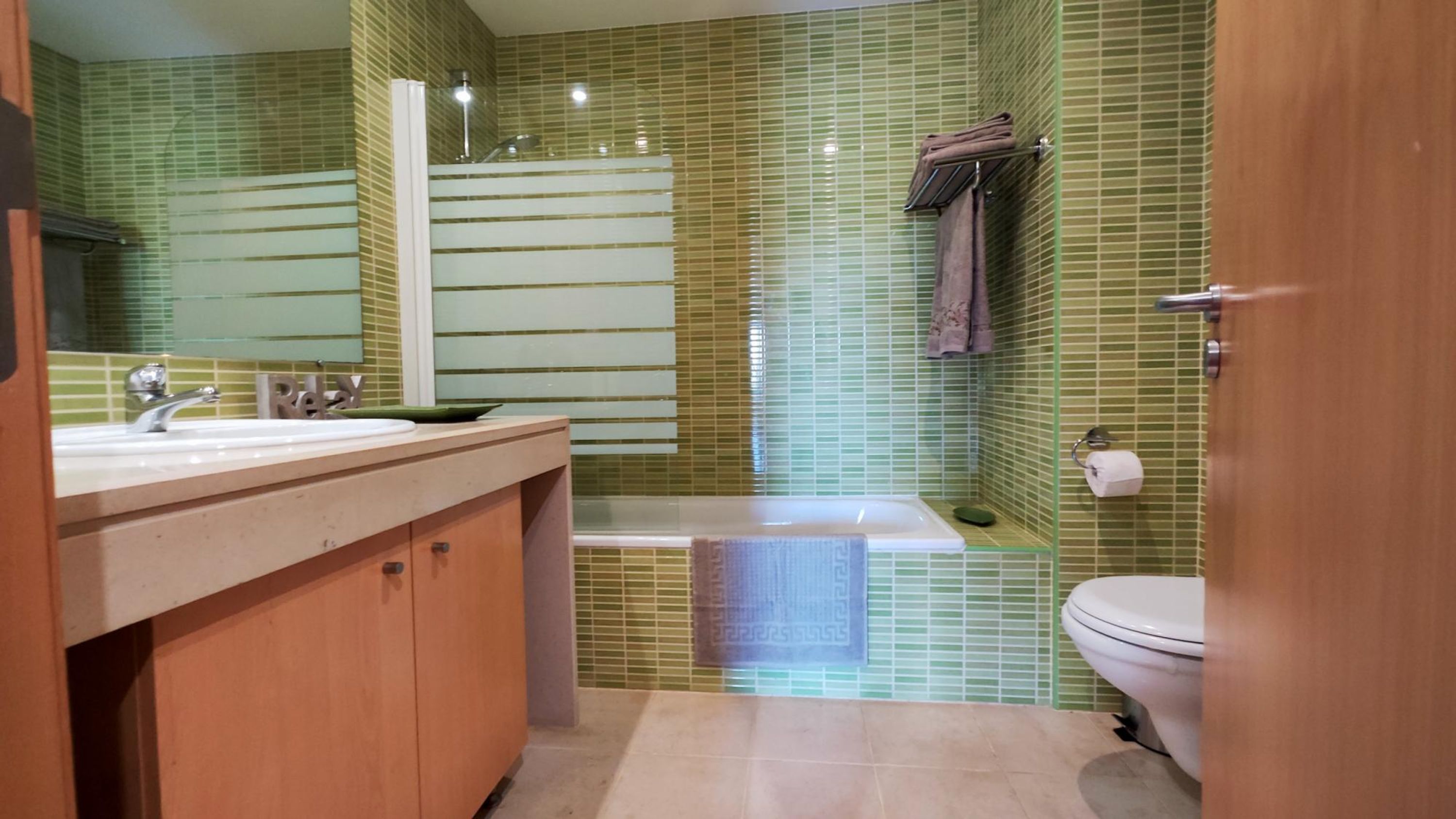 Une salle de bain avec un meuble-lavabo en bois, une baignoire et des toilettes.