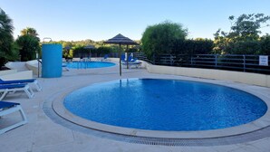 Une piscine avec des chaises longues et un kiosque.