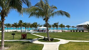 A resort with a pool area, palm trees, and a beach view. - Fabulous beachfront condo (Treasure Cay)