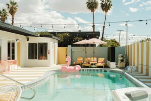 Un espace piscine agrémenté d’un flotteur en forme de flamant rose, de chaises longues et d’un palmier en arrière-plan.