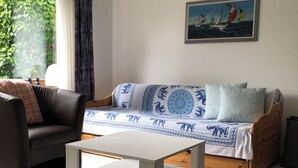 Een woonkamer met een bank, een bijzettafeltje en een schilderij aan de muur.