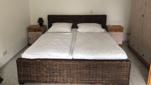 Een tweepersoonsbed met een donker hoofdbord, twee nachtkastjes en een kledingkast.