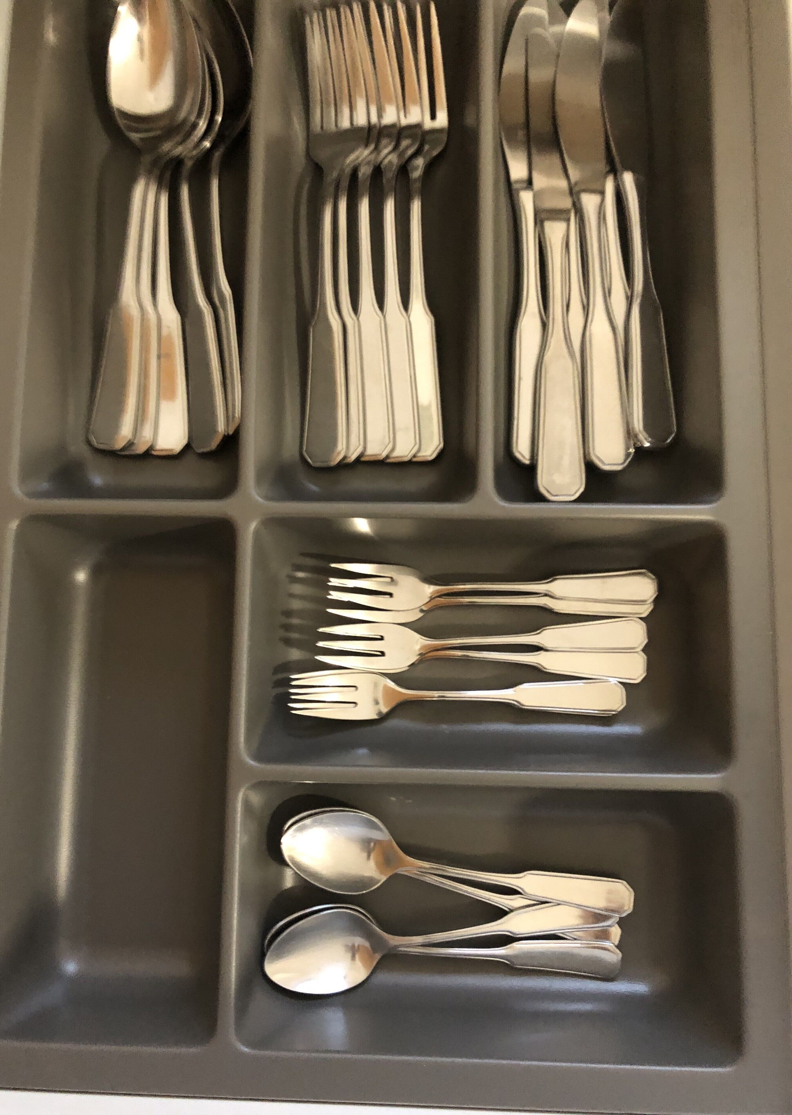 Una bandeja compartimentada con varios utensilios de cubertería, incluyendo tenedores, cucharas y cuchillos.