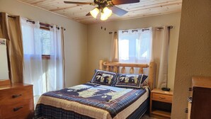 A bedroom with a wooden bed, a nightstand, a dresser, and a ceiling fan. - Sutter Northwoods Home (Eagle River)
