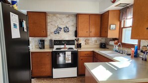 A kitchen with wooden cabinets, a stove, a refrigerator, and a sink. - Sutter Northwoods Home (Eagle River)