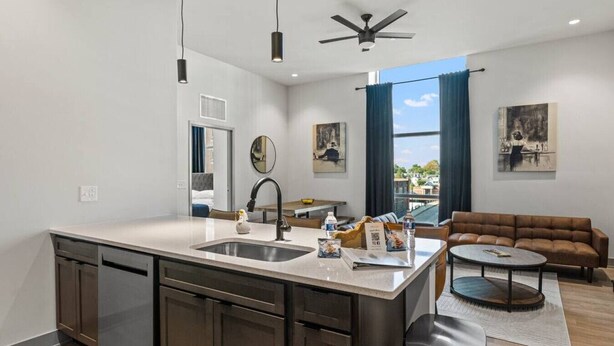 A modern kitchen with a central island, a dining area with a round table, a sofa, and artwork on the walls. - Bourbon Condo Downtown Lexington (Lexington)