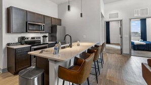 A modern kitchen with a central island, stainless steel appliances, and a coffee bar. - Bourbon Condo Downtown Lexington (Lexington)