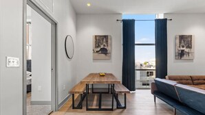 A modern living room with a wooden dining table, a sofa, and artwork on the walls. - Bourbon Condo Downtown Lexington (Lexington)