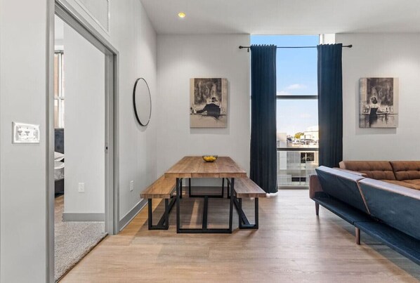 Una sala de estar moderna con una mesa de comedor de madera, un sofá y obras de arte en las paredes.