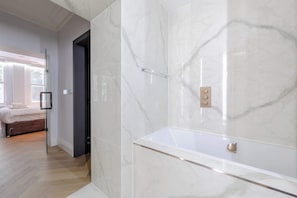 Un baño moderno con ducha de mármol y bañera.