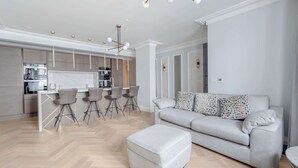 Ein modernes Wohnzimmer mit grauem Sofa, passendem Hocker und einem Essbereich mit Barhocker.