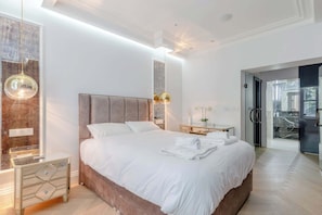 Un dormitorio moderno con una cama grande, una mesita de noche, un espejo y un vestidor.