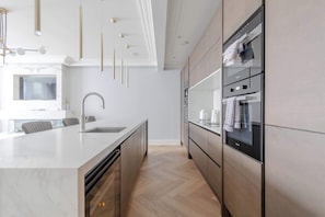 Une cuisine moderne dotée d’un grand îlot central, d’appareils électroménagers intégrés et d’un design minimaliste.