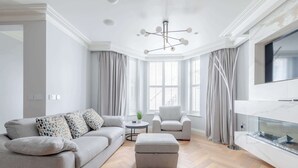 Ein modernes Wohnzimmer mit einem grauen Sofa, einem weißen Sessel und Holzboden.