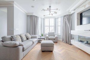Un salon moderne avec un canapé gris, un fauteuil blanc et un plancher en bois.