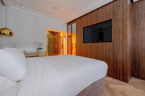 Un dormitorio moderno con una cama grande, un televisor instalado en la pared y un armario de madera.