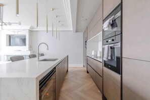 Une cuisine moderne dotée d’un grand îlot central, d’appareils électroménagers intégrés et d’un design minimaliste.