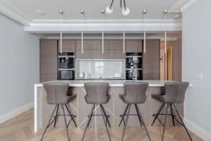 Une cuisine moderne dotée d’un îlot central, de tabourets de bar et de luminaires suspendus.