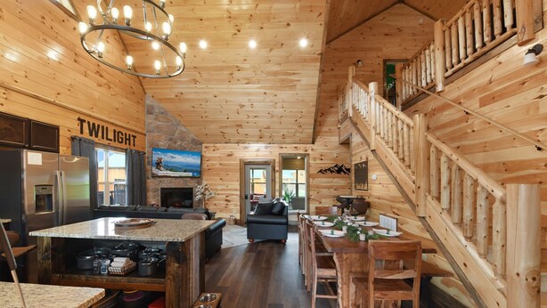 A spacious log cabin interior with a kitchen, dining area, and a staircase.