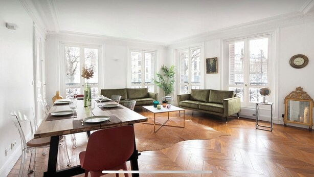 Un vaste salon comprenant un coin repas, de grandes fenêtres et une vue sur la ville.