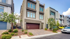 A modern multi-story residential building with a garage, landscaped garden, and a parked vehicle. - Las Vegas Home w/ Terrace ~ 10 Mi to the Strip! (Las Vegas)
