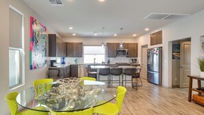 A modern kitchen with a glass dining table, bright yellow chairs, stainless steel appliances, and wooden cabinets. - Las Vegas Home w/ Terrace ~ 10 Mi to the Strip! (Las Vegas)