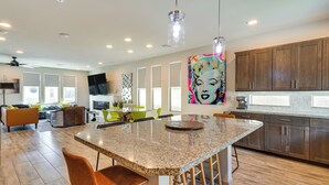 A modern kitchen with a granite island, wooden cabinets, and a large window. - Las Vegas Home w/ Terrace ~ 10 Mi to the Strip! (Las Vegas)