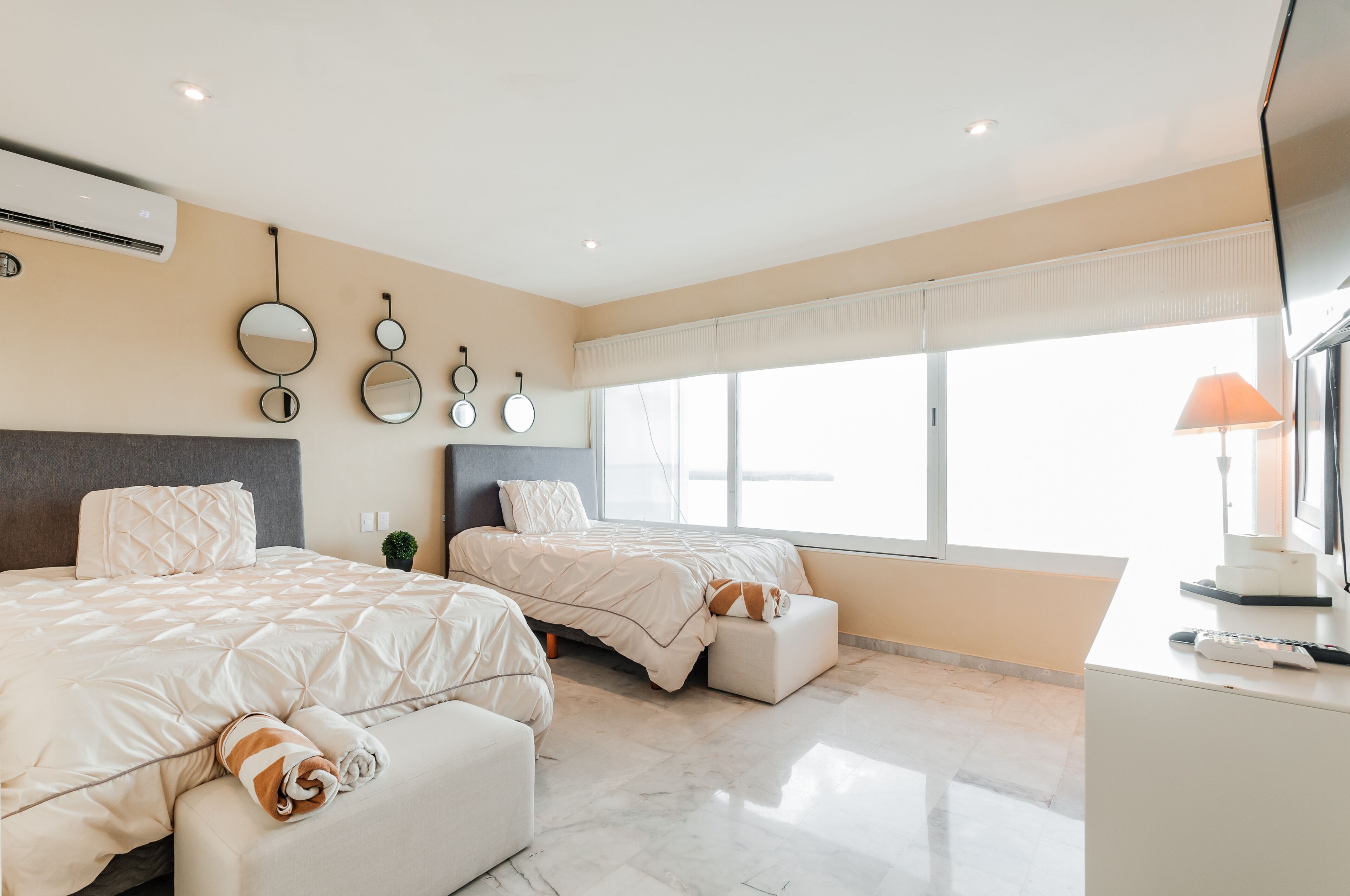 Una habitación de hotel moderna con dos camas, un escritorio y un ventanal grande.