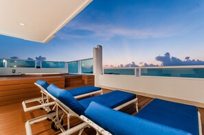 A deck with lounge chairs and a glass balustrade overlooking a body of water.